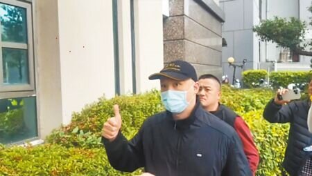 涉與台中「五億高中生」賴小弟假結婚的同婚配偶夏朝源(前),被依偽造文書案判刑1年6個月,3日由警方陪同到台中地檢署報到,下車時被問及「有沒有什麼話要說?」突豎起大拇指比讚。(馮惠宜攝)