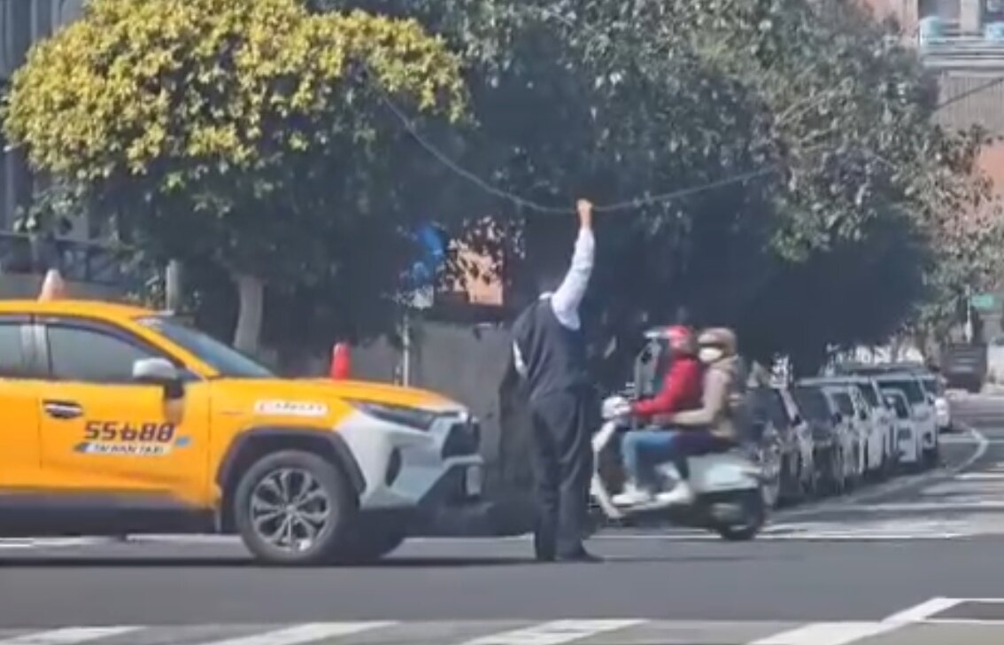 司機大哥獨自站在路口撐起垂落的線，避免了機車騎士或其他被勾到危險事情發生。圖：翻攝自Threads-old.tseng