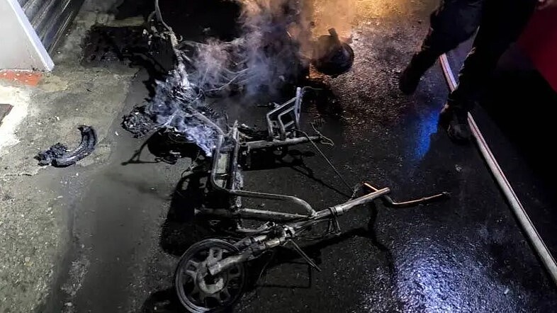 高雄市仁武區華北街一棟公寓26日凌晨2時許傳出火警,1樓樓梯間停放的2輛電動機車被燒成廢鐵。圖/記者石秀華翻攝