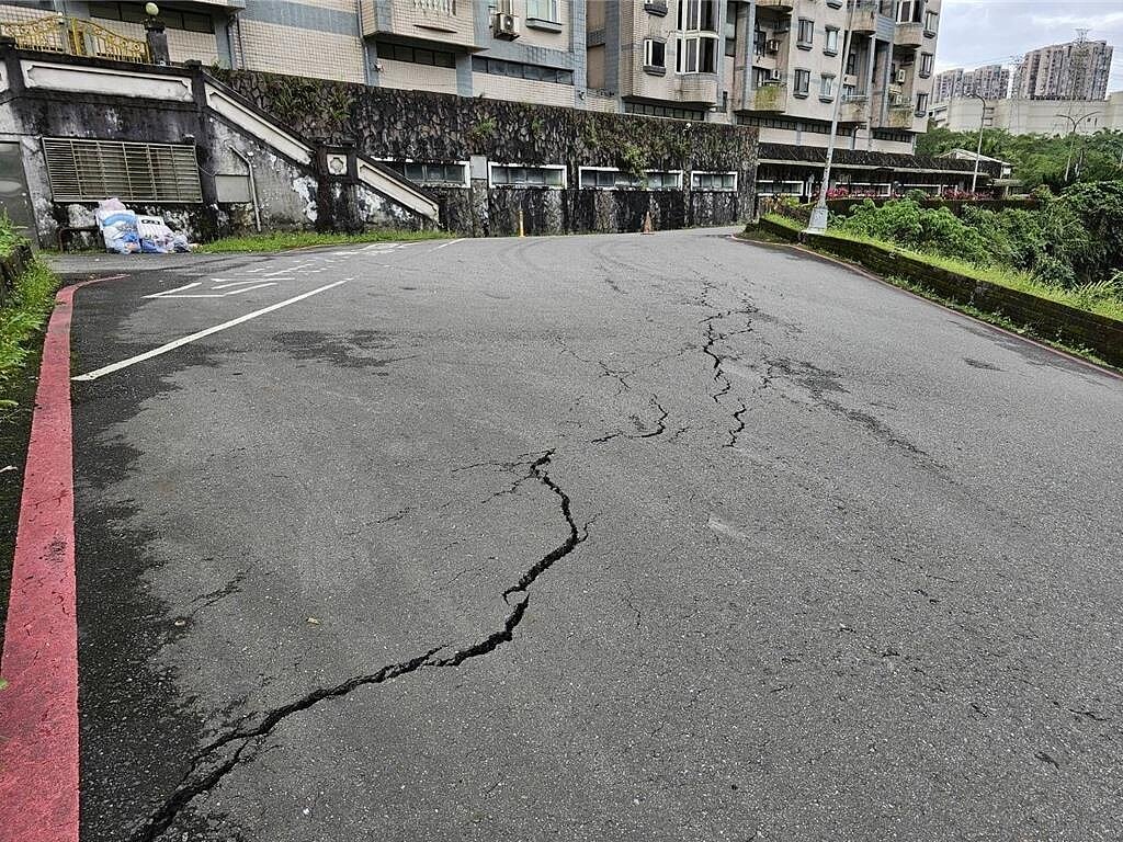 汐止伯爵街發生地面龜裂傾斜的狀況,目前已由警方前往設置封鎖線雙向管制並實施交通疏導,另外也通知區公所派廠商前往處理。圖/翻攝畫面