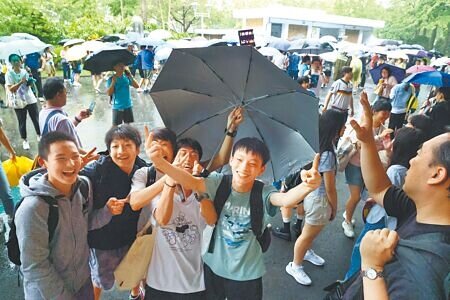 國中會考18日考試剛結束,台北下起傾盆大雨,師大附中考場考生撐傘開心地衝出考場。(鄧博仁攝)