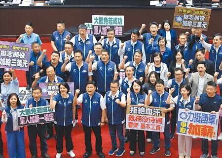 立法院10日三讀通過《軍人待遇條例》部份條文修正草案,國民黨立委拿著標語在議場拍照留念。(姚志平攝)