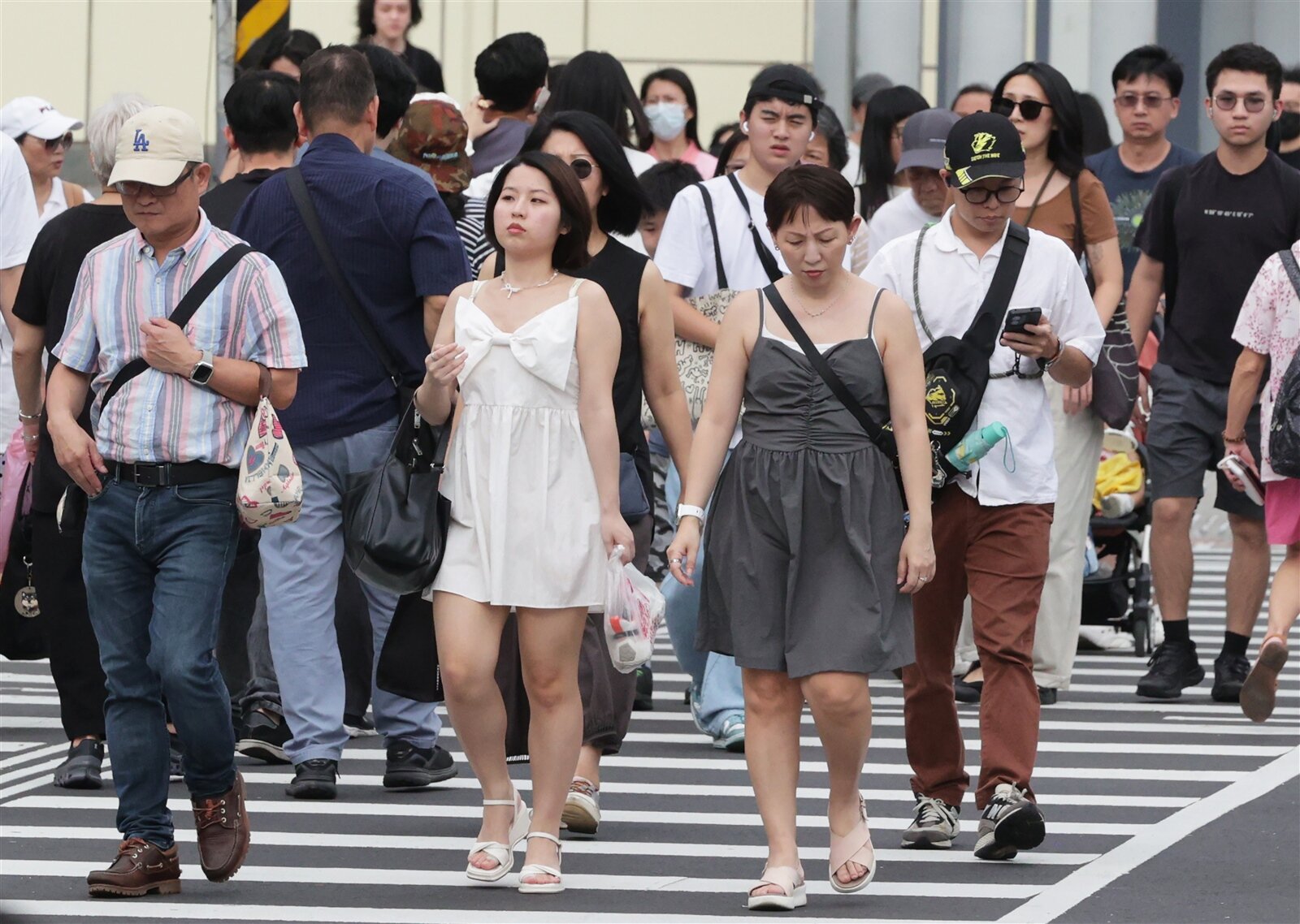 昨天水氣減少陽光露臉,許多民眾穿著夏裝上街,或是撐傘、拿著小風扇抵抗艷陽,今高溫更上看38度 。記者潘俊宏/攝影