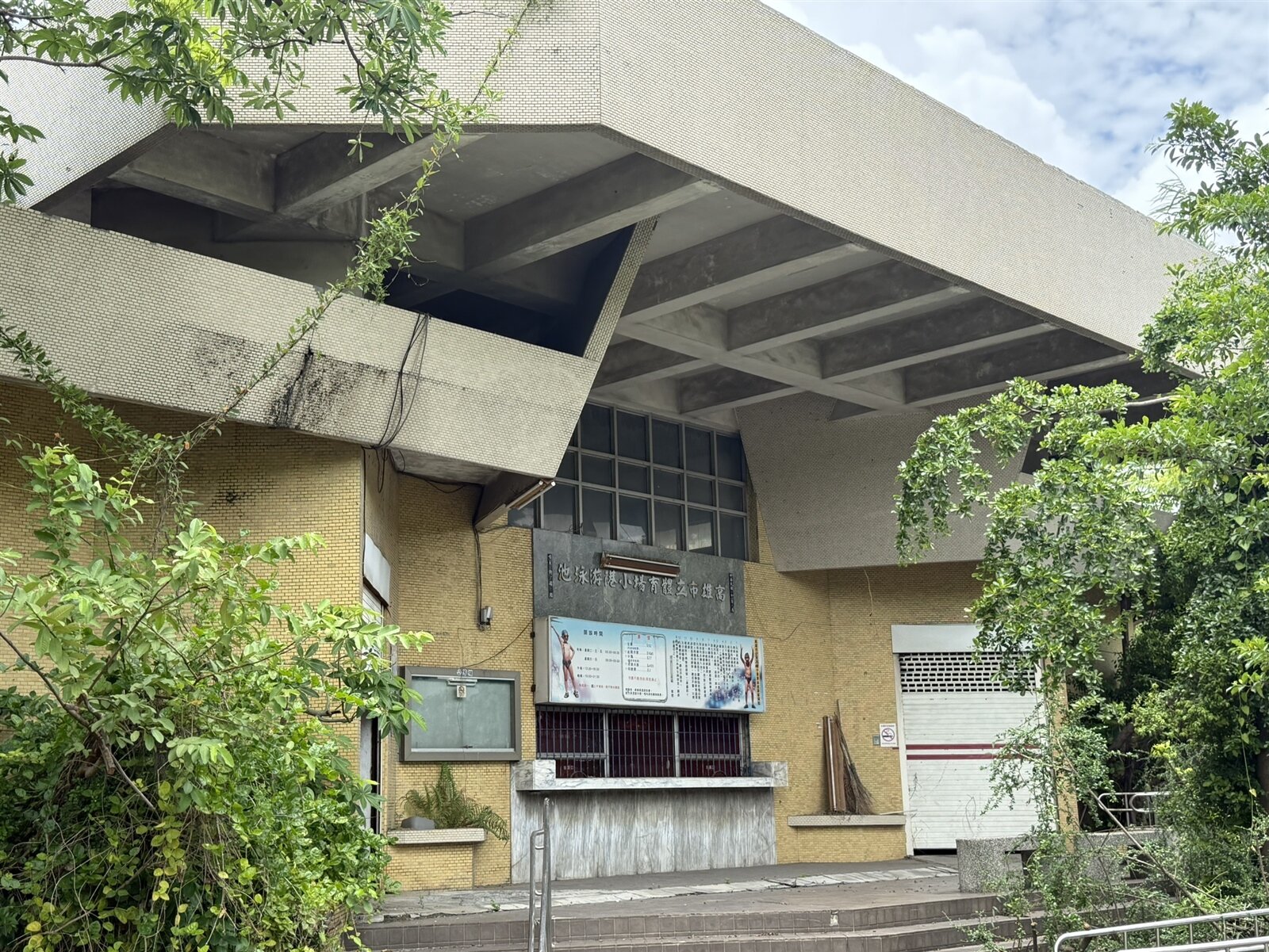 高雄市立小港泳池荒廢20年以上,去年底泳池填平,改作停車場,但泳池旁建物因耐震不足將全數拆除,卻無具體進度。記者宋原彰/攝影