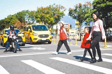 第一線交警指出,法規無行人過馬路滑手機罰則。但交通部解釋,在行穿線滑手機若影響交通可罰500元。示意圖為家長牽著小朋友過馬路畫面。(本報資料照片)