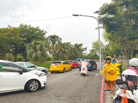 高雄左營區新上國小北側門旁有塊市府用地雜草叢生,家長只能靠邊停接送,碰到下雨天車流回堵嚴重。(紀爰攝)