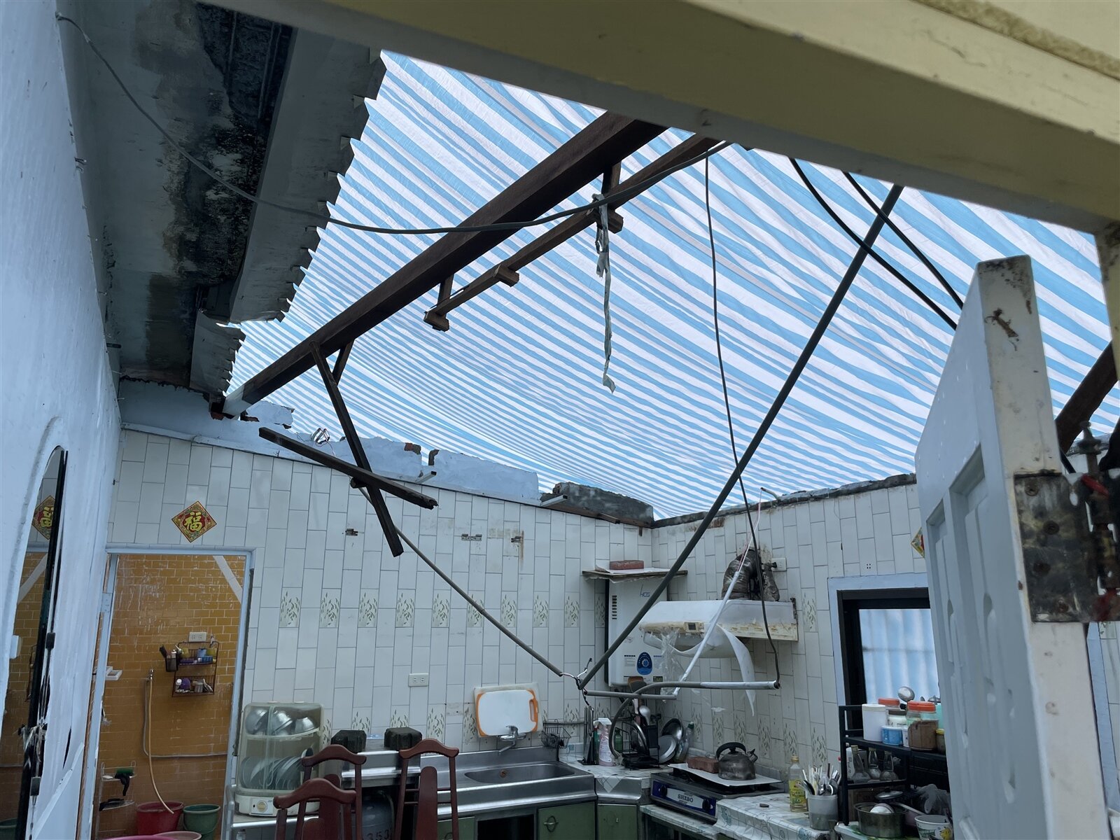 台南柳營近8旬婦人住家的廚房鐵皮屋頂被吹走，雨水不斷滲入，昨終於覆蓋帆布。記者萬于甄／攝影 
