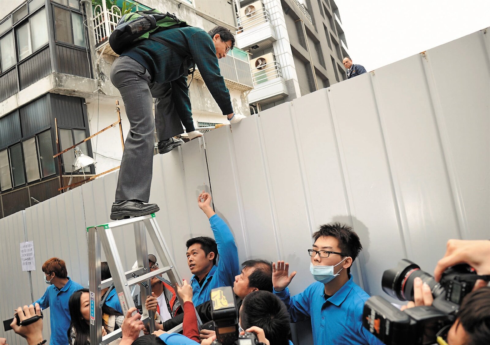 士林文林苑王家所設組合屋,上午由王家擁有土地所有權的王耀德自行帶拆除人員拆除。律師詹順貴爬進工地內聲援,工地工人阻止不及。 記者林澔一/攝影