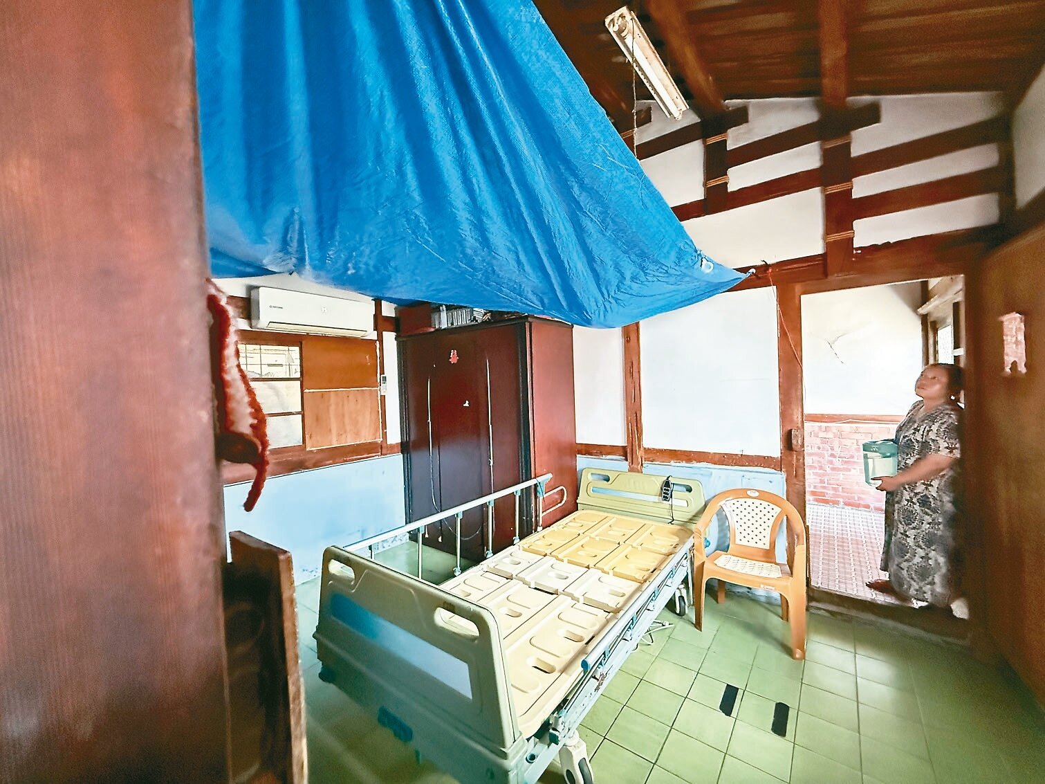 嘉義縣水上鄉6旬婦人苦守漏水屋照顧公婆,前晚突然下起大雨,她只能先在床榻上拉起帆布接水。記者黃于凡/攝影