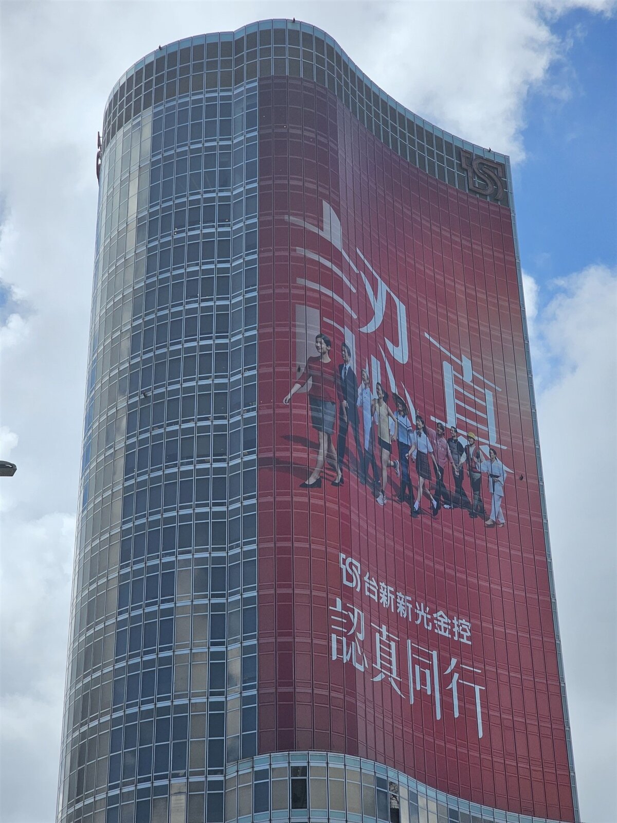 台新新光金控24日舉行合併揭牌儀式，總部大樓已率先換上新裝，布幕上出現四字標語：「認真同行」。記者戴玉翔／攝影 