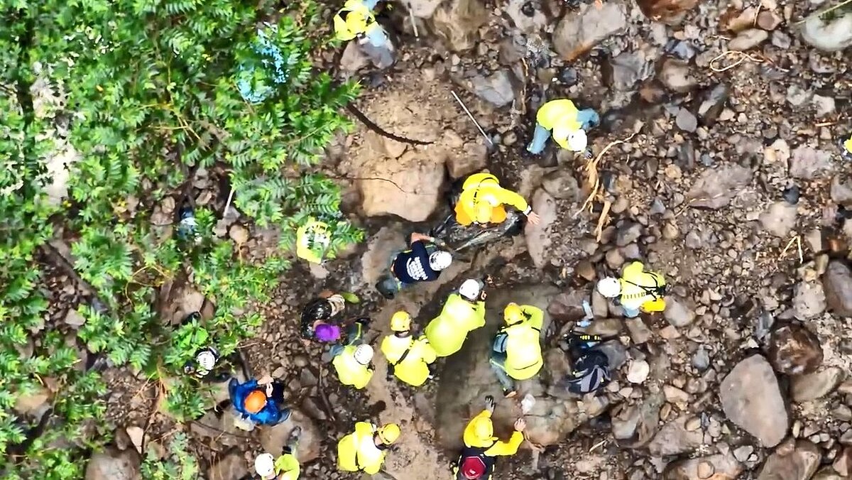高市消防局特搜和救難人員在上游處發現墜谷的李男車子,車體有90%被埋在地底裡,且有大石頭卡住,因無法以重機具,只能先徒手持工具開挖。圖/記者石秀華翻攝