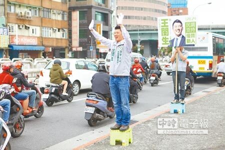 參選大安文山區市議員的前民進黨中央黨部發言人王閔生,清早站在路口拜票爭取支持。(張立勳攝)