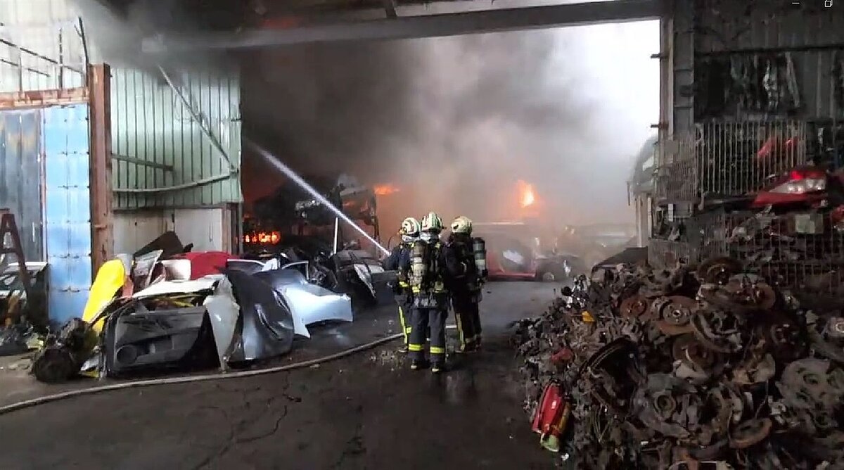 台中市大里區中投東路旁汽車中古材料行16日中午因不明原因起火,消防員到場灌救。圖/讀者提供