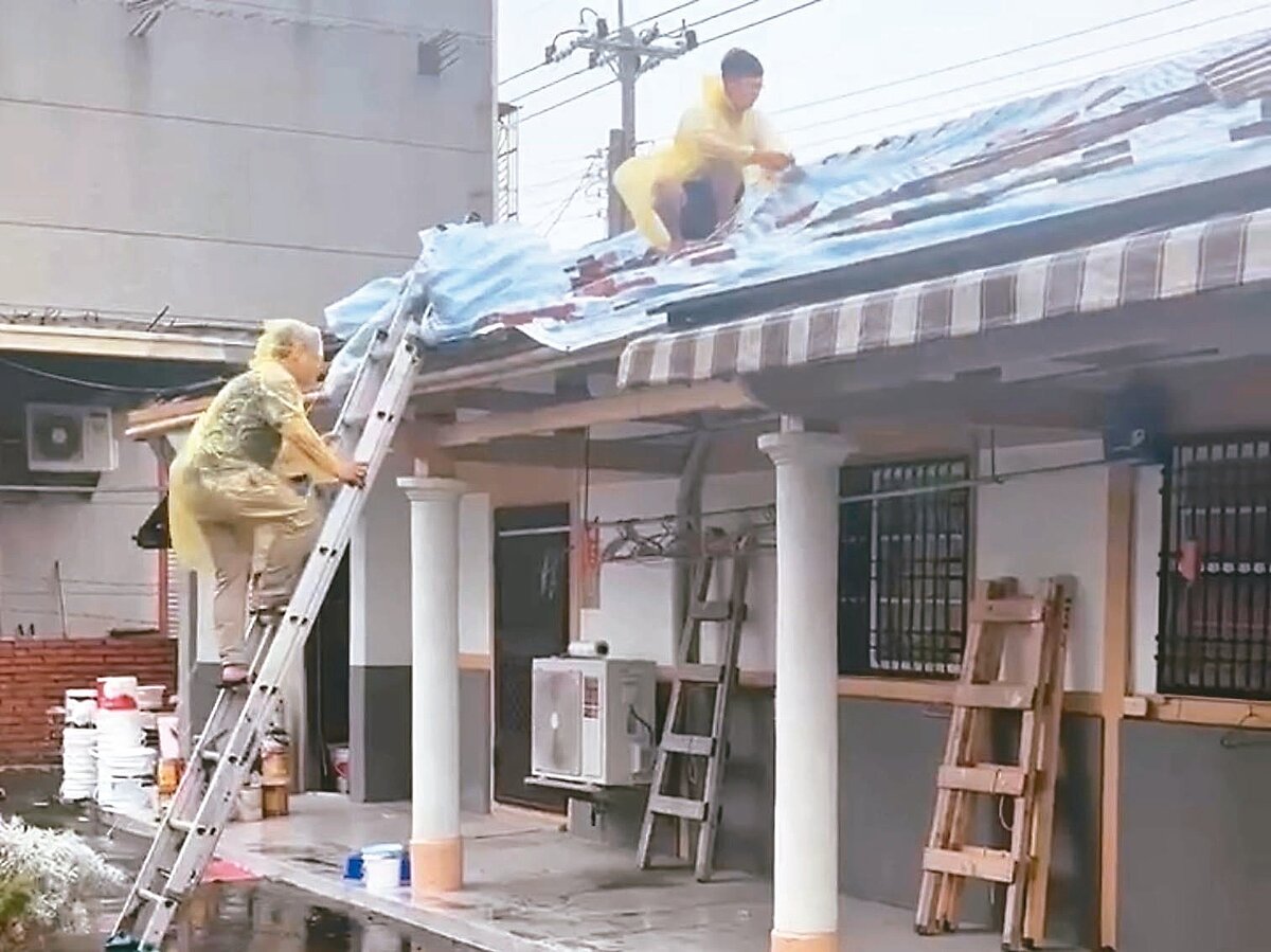 嘉義縣水上鄉一處民宅屋頂帆布被強風吹翻,受災戶只能穿雨衣冒雨爬上屋頂。圖/民眾提供
