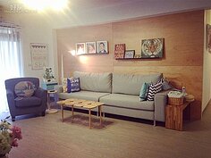 客廳擺設藍色布沙發，茶几很有特色，牆上則掛著蔡逸帆的油畫作品。