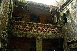 洋樓後方左右由兩棟側棟包圍成凹字型，但也因為靠山潮溼，看起來頗為破舊。(好房記者張聖奕/攝影)