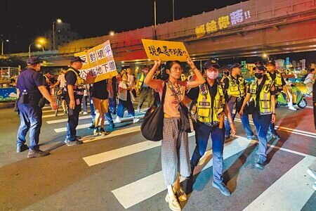 台北市政府拆除公館圓環並填平公車專用地下道,引發部分民眾反彈,民團與在地學生12日晚間舉辦「守環行動:圓環大走讀」活動,號召民眾到圓環抗議。圖為抗議民眾手舉標語表達訴求。(郭吉銓攝)
