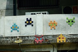 抬頭一看，二樓圍牆上所設計的裝置藝術，就是八位元電玩時期最風彌大眾的「小蜜蜂」電動玩具中的小蜜蜂。