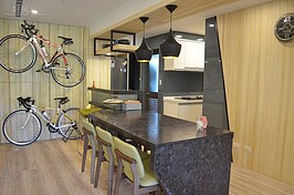 餐桌也採用石材，旁邊還有個小吧檯，一旁牆面擺放兩台自行車，是實用又好看的設計。