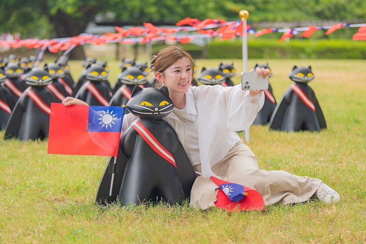桃園國慶升旗典禮明早8時在風禾公園舉行,今年以「國慶齊聚.桃園永續」為主題,結合「黑貓出任務」活動,70隻黑貓公仔9日已整隊現身,吸引不少遊憩民眾目光。圖/桃園市民政局提供