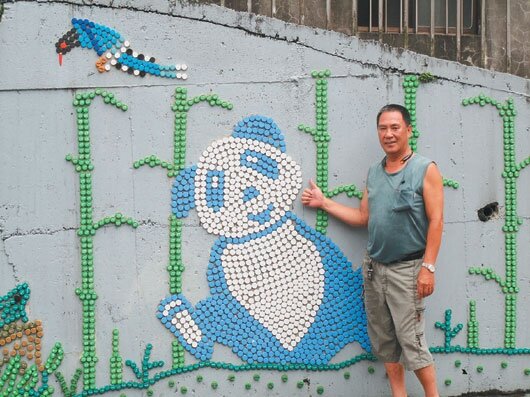 信義區東明里里長賴賢義以回收舊瓶蓋,拼貼出鮮豔壁畫,圖為他與最喜歡的貓熊作品。(記者林孟潔/攝影)