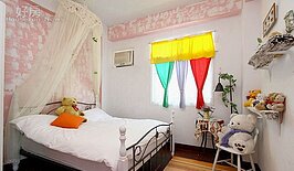 以白色的床為主，搭配鮮艷的窗簾，還有可愛的小熊擺設。
