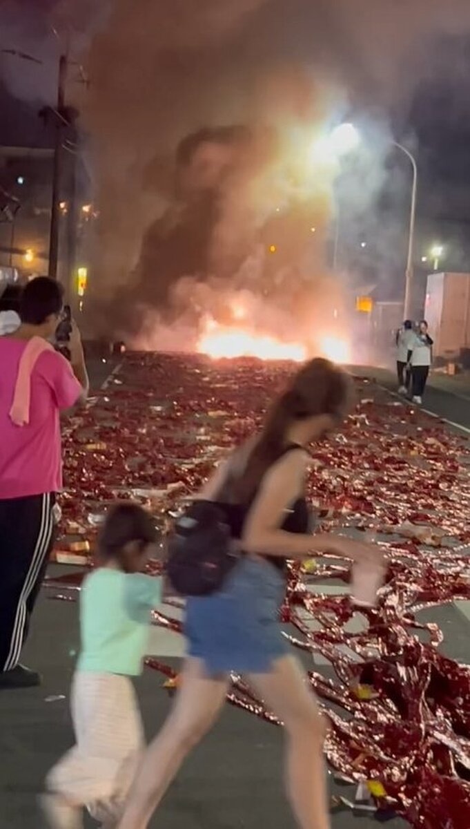 高市仁武區某廟宇昨晚在合法申請的廟會遶境街道誇張鋪滿整條街的紅色鞭炮後燃放，年輕媽媽帶小女孩嚇得快步走過。圖／取自臉書社團{仁武人}※大小事