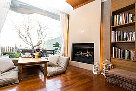 客廳的落地窗前，是來此住宿的房客最喜歡窩的地方。為了讓房客在冬天也有一個舒適溫暖的環境，客廳一角還有壁爐。