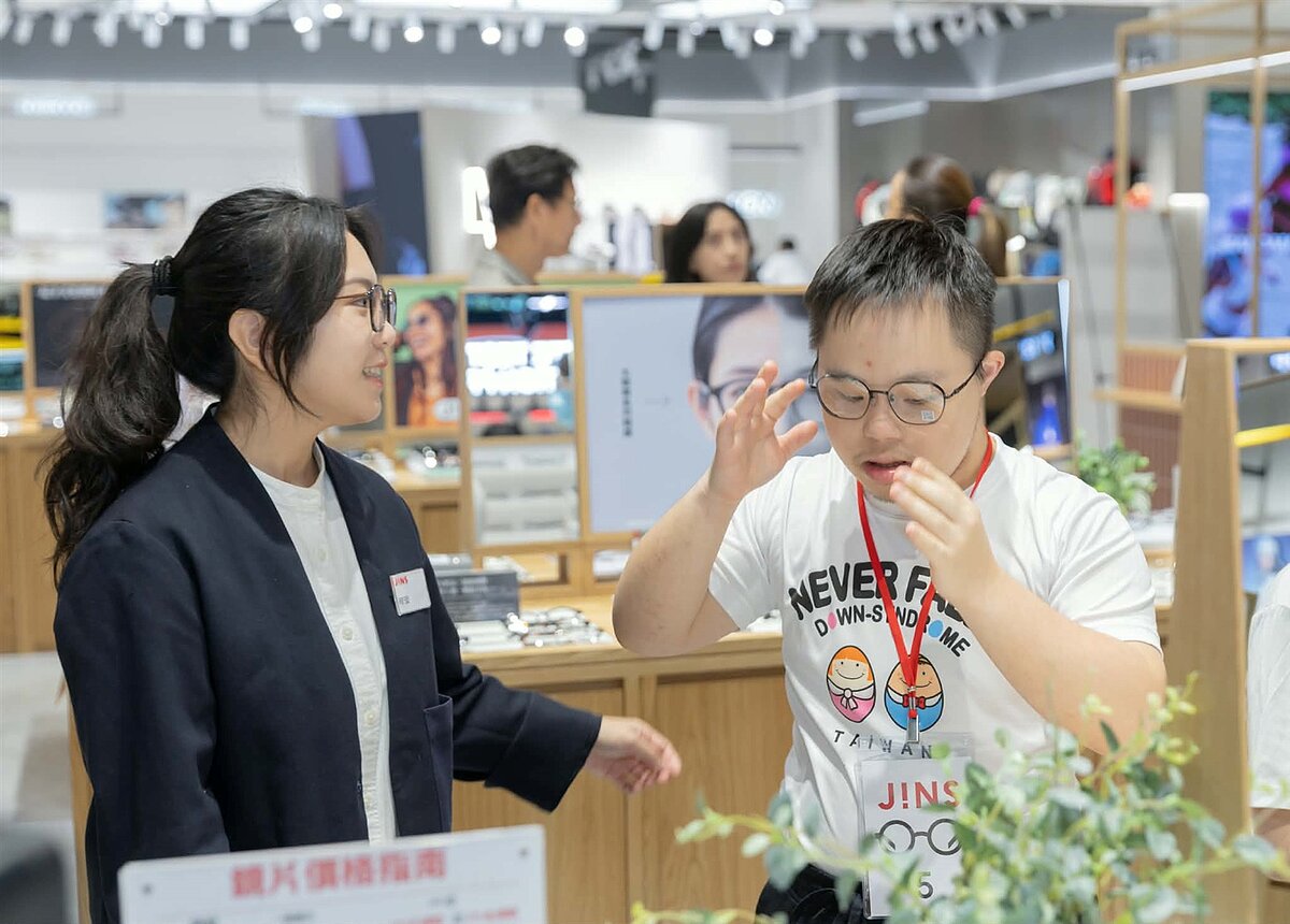 JINS舉辦唐寶寶免費公益配鏡活動，店鋪人員陪同配鏡者挑選、試戴眼鏡。圖／JINS提供
