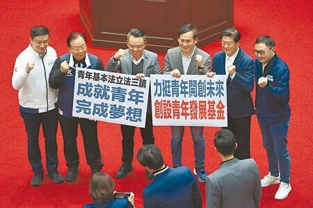 
立法院26日院會三讀通過「青年基本法草案」，國民黨立委在議場內拿著標語合影留念。（姚志平攝）
