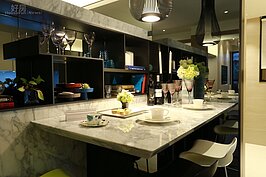 餐桌與客廳間用一堵貼著石材的牆作為區隔，若是預算不夠，或者要營造更大的空間感，牆不用頂到天花板，可降低高度留出視線互通空間。