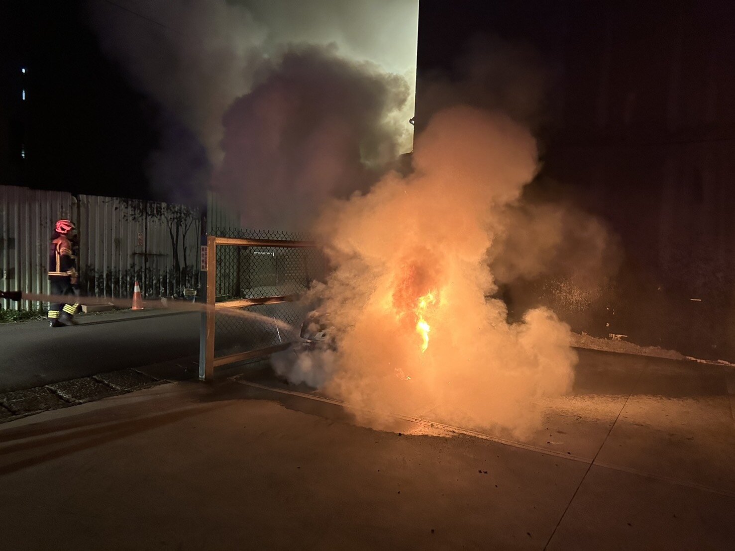 消防員架設水線灌救,防止火勢延燒至鄰近住宅及周邊車輛。圖:讀者提供