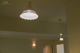 客廳中並沒有傳統的單一多顆燈泡主燈，也不是採用現在流行的包覆天花板後裝入嵌燈，而是採用兩個蕾絲吊燈以及壁燈當照明用燈，三組燈飾五千元有找。