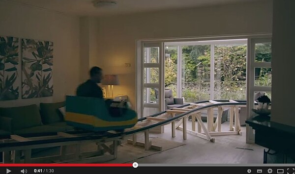 荷蘭有業者推出搭乘雲霄飛車看屋的活動,被委售的房子會在室內搭建簡單的軌道及迷你的雲霄飛車。(翻攝自Youtube)