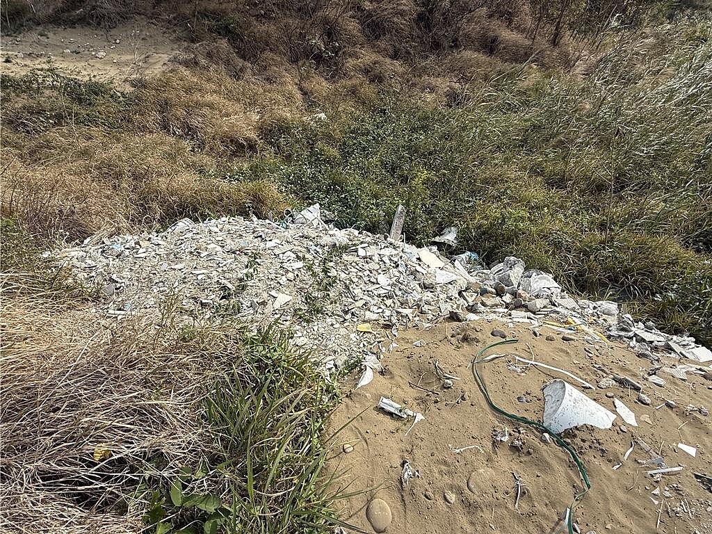 竹南鎮新崎頂段一處空地,居民反映夜間有人焚燒廢棄物,濃烈塑膠惡臭隨風飄散至龍鳳漁港周邊。苗栗縣環保局會同警方稽查發現,現場堆置物多為營建垃圾,且已棄置一段時間。(呂麗甄攝)