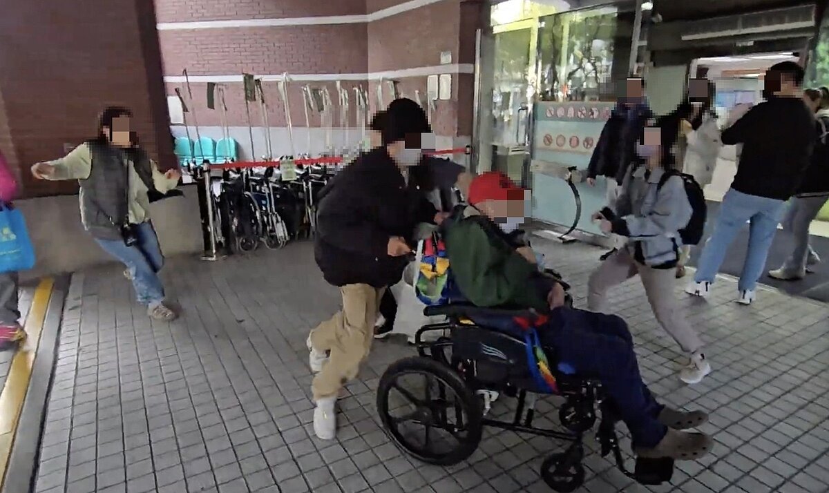 王姓人瑞（坐輪椅戴紅帽）跟看護賴婦（左一）1月結婚，日前人瑞的子女趁父親回診，在醫院外「搶人」。圖／民眾提供
