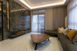 客廳沒有令人眼花撩亂俗氣的設計，而是以石版為牆，L形的沙發打造出精緻沈穩內斂的視覺感受。