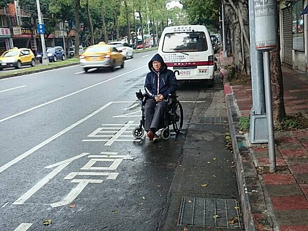 輪椅客在路上等公車顯得很渺小。(圖/吳光中)