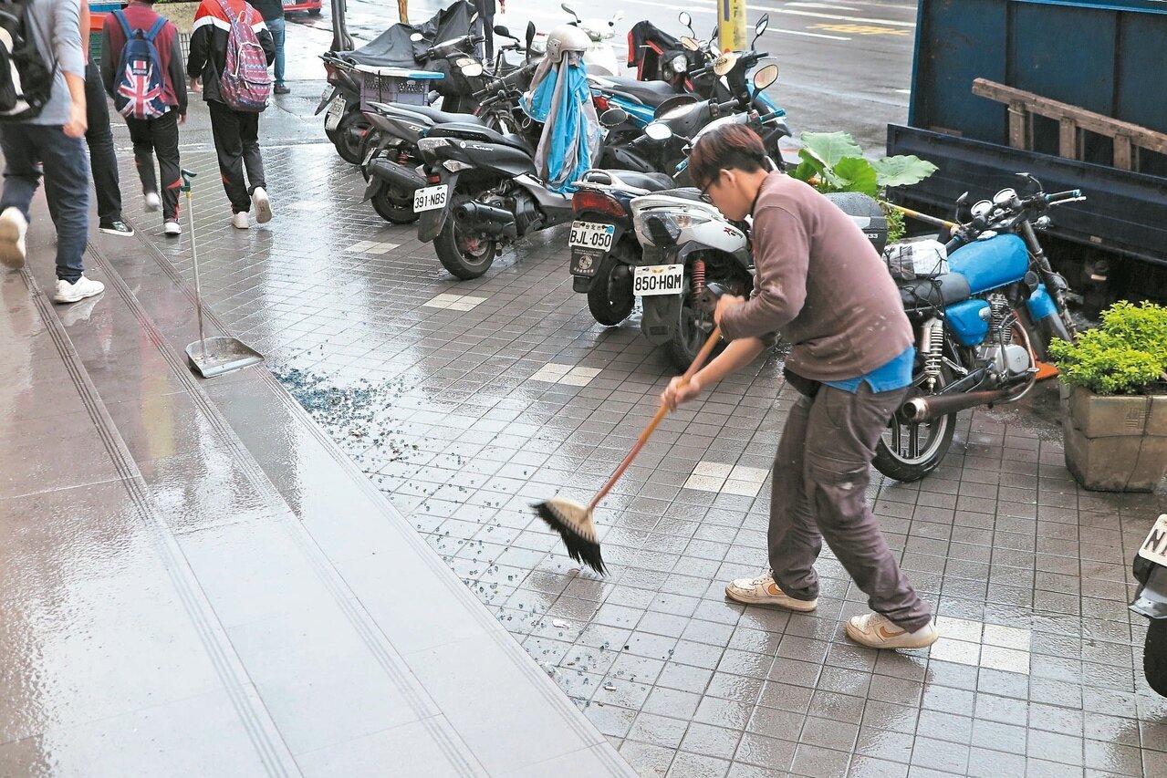基隆皇冠大樓4樓整修，疑未做好防護措施，讓碎玻璃砸落1樓人行道，廠商忙著清掃。 記者林孟潔／攝影